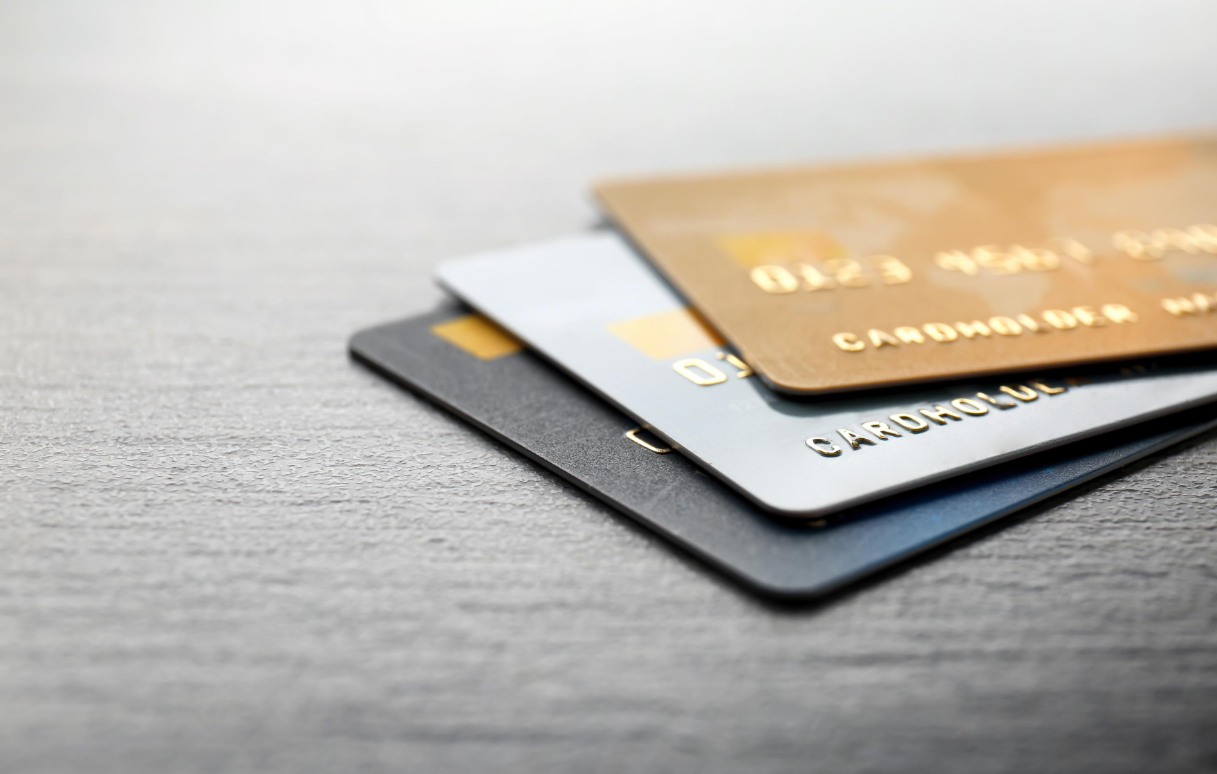 How can I improve my credit rating? Close up shot of three credit cards stacked on top of one another on a desk.