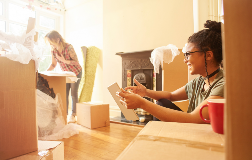 Two young girls unpacking cardboard boxes after buying their first home.