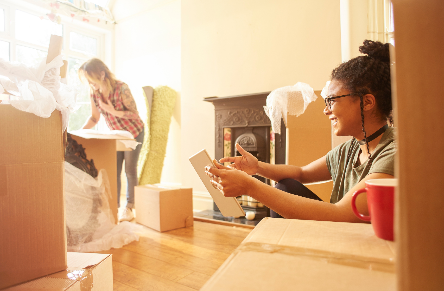 Two young girls unpacking cardboard boxes after buying their first home.