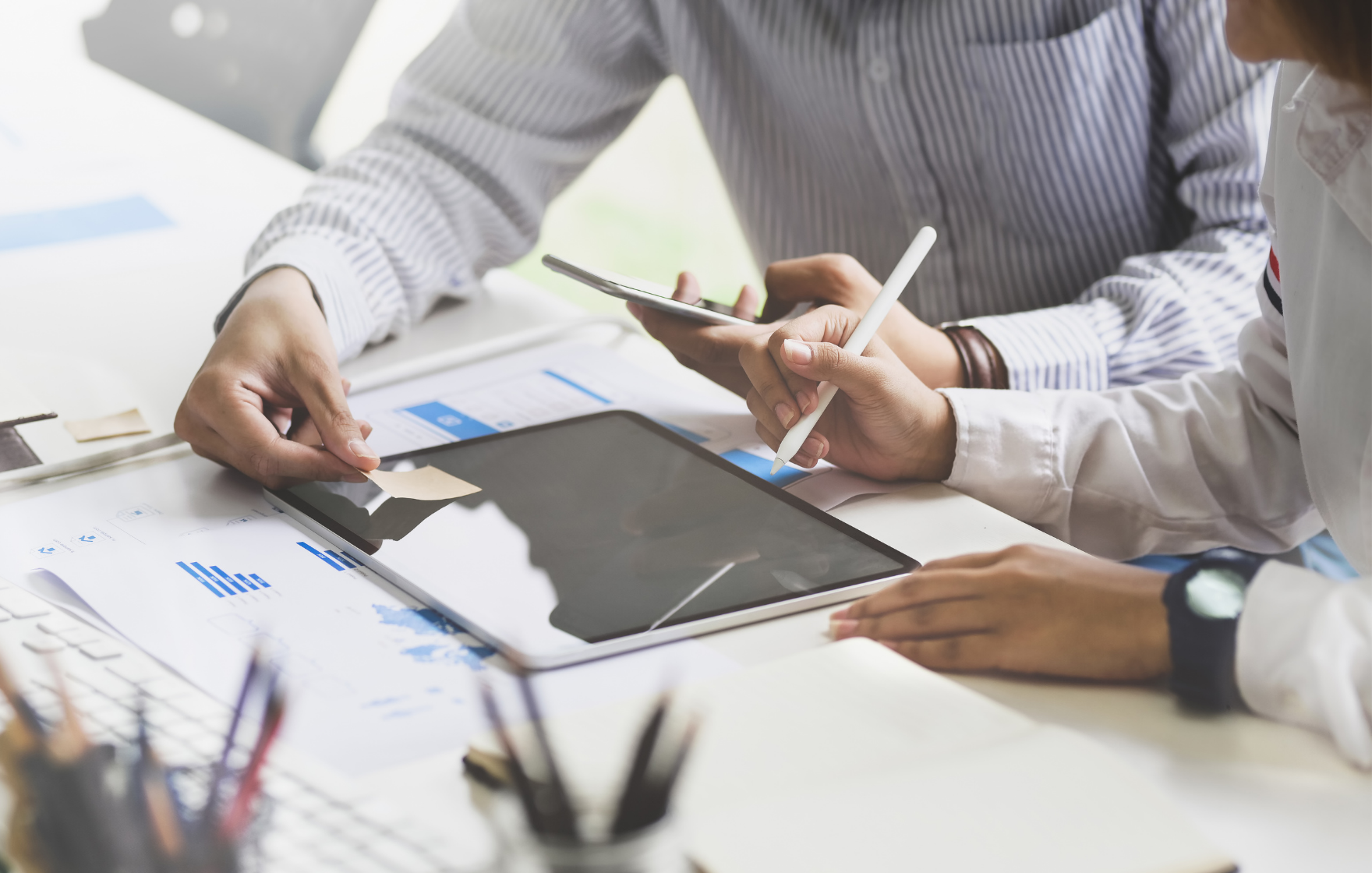 Close up image of man and woman discussing the advantages of cash flow forecasting with a tablet, paperwork and mobile in hand.