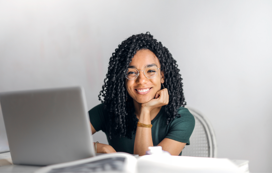 Woman sits in front of laptop smiling at the camera