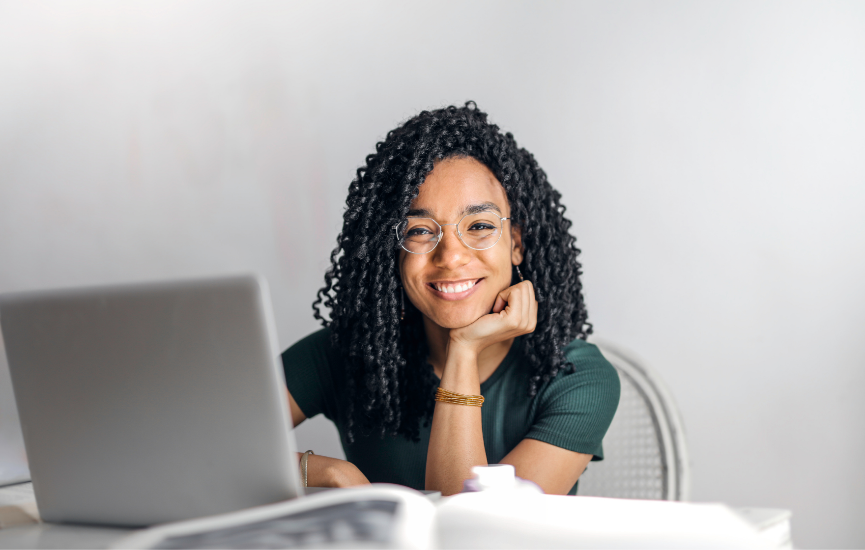 Woman sits in front of laptop smiling at the camera
